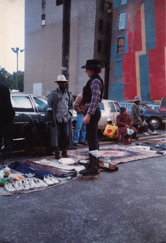 WHEEL THING...a cowboy on roller-skates speaks to people selling their belongings on street