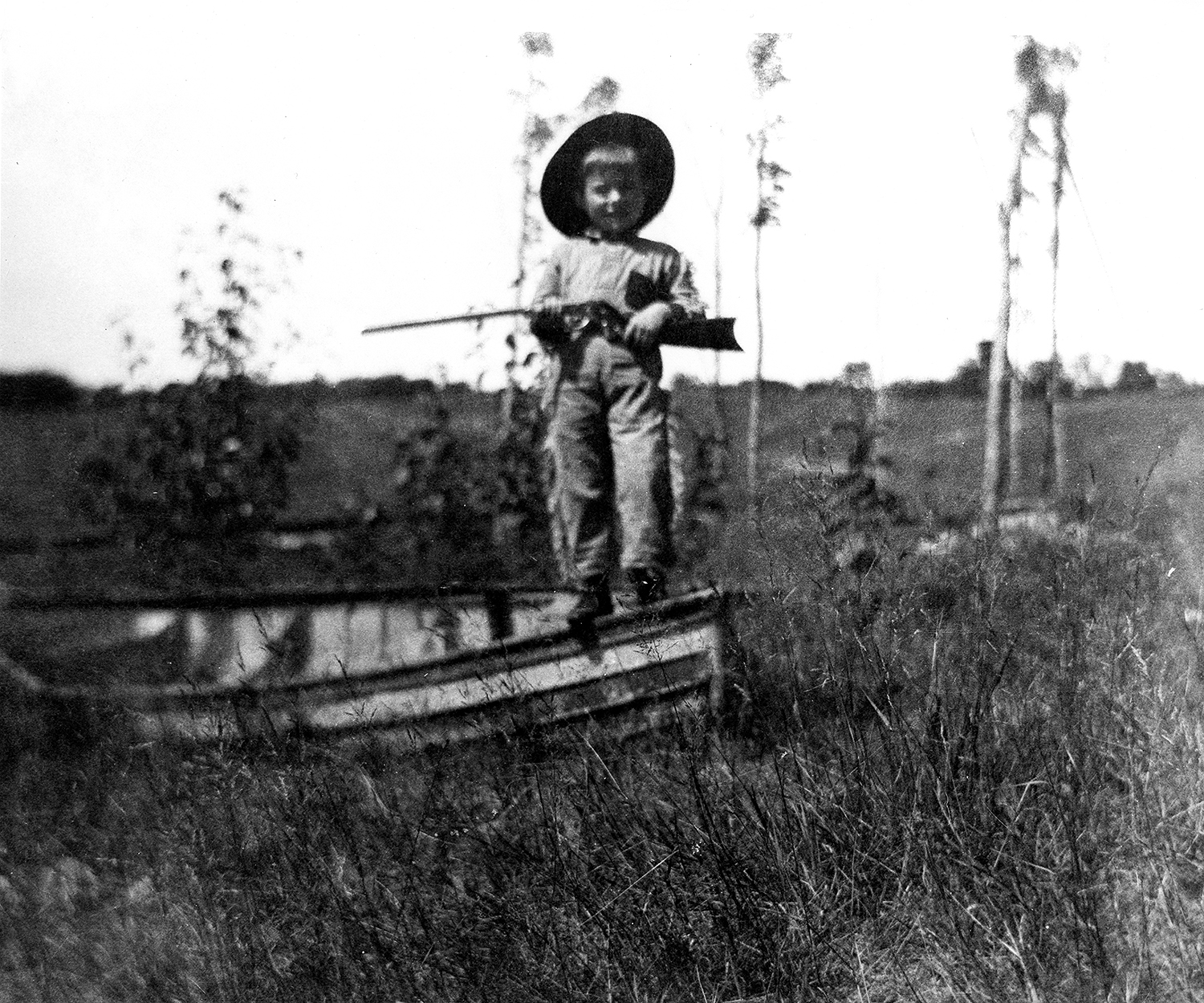 CHILDHOOD...Ernest Hemingway holding a gun at Walloon Lake. Copyright: Public Domain